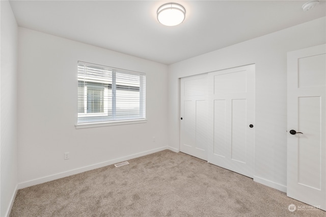 unfurnished bedroom featuring a closet and light carpet