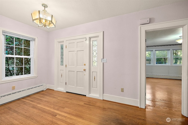 foyer entrance with hardwood / wood-style floors, a healthy amount of sunlight, and baseboard heating