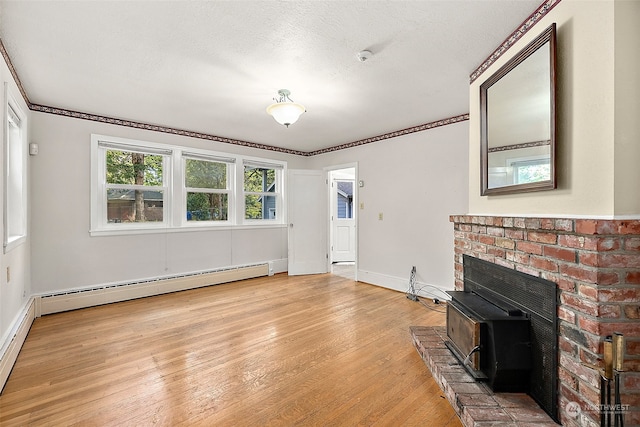 unfurnished living room featuring a baseboard heating unit, a textured ceiling, ornamental molding, light hardwood / wood-style floors, and a wood stove