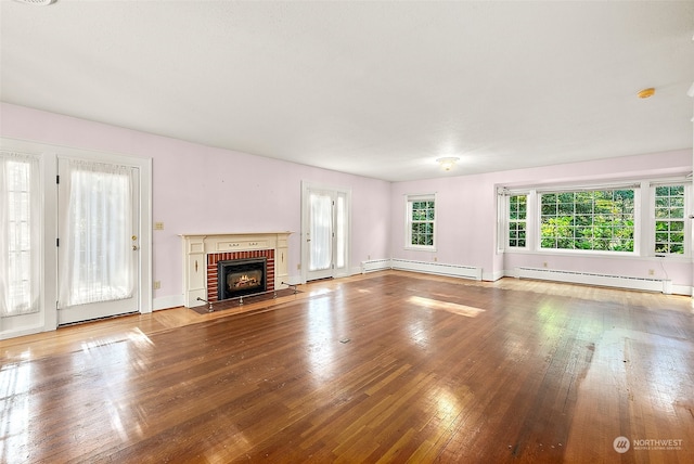 unfurnished living room featuring baseboard heating, hardwood / wood-style floors, and a brick fireplace