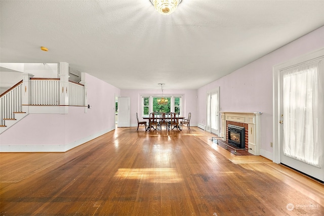 unfurnished living room with baseboard heating, a textured ceiling, a fireplace, and hardwood / wood-style flooring