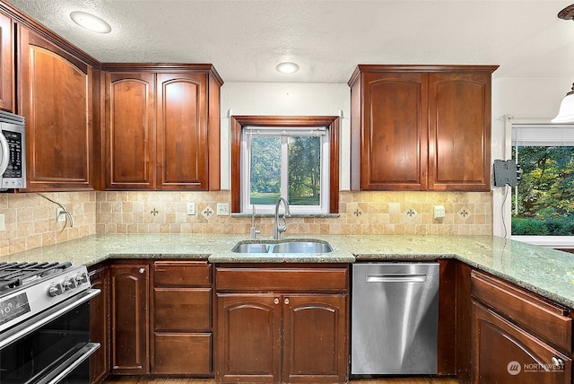 kitchen with tasteful backsplash, light stone countertops, stainless steel appliances, and sink