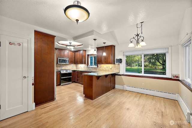 kitchen with kitchen peninsula, hanging light fixtures, light hardwood / wood-style floors, stainless steel appliances, and vaulted ceiling