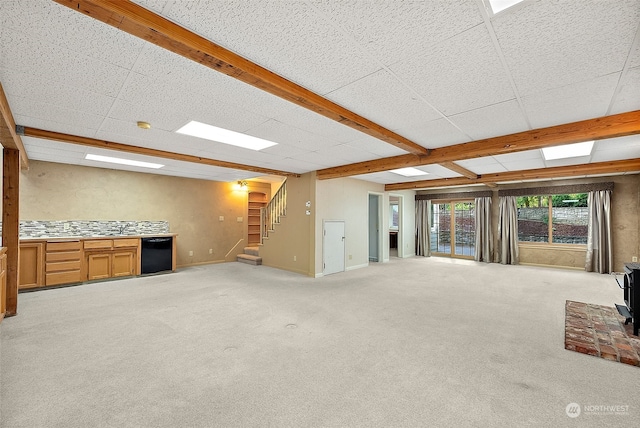 unfurnished living room featuring light carpet, a wood stove, and beam ceiling