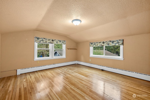 bonus room with lofted ceiling, a baseboard heating unit, a textured ceiling, and hardwood / wood-style flooring