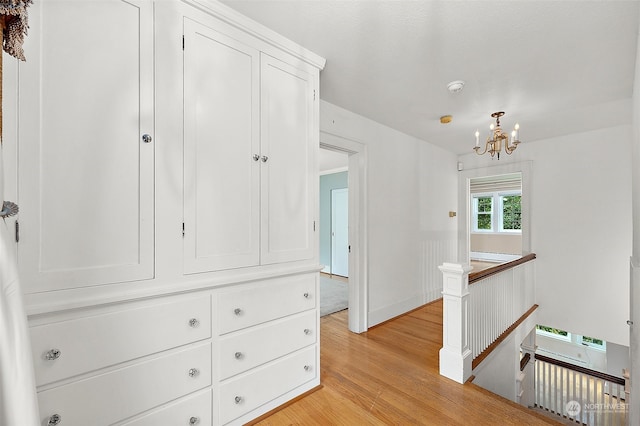 hallway featuring a notable chandelier and light hardwood / wood-style flooring