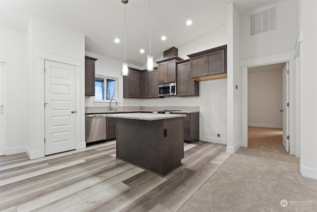 kitchen with dark brown cabinetry, a center island, light hardwood / wood-style flooring, decorative light fixtures, and appliances with stainless steel finishes