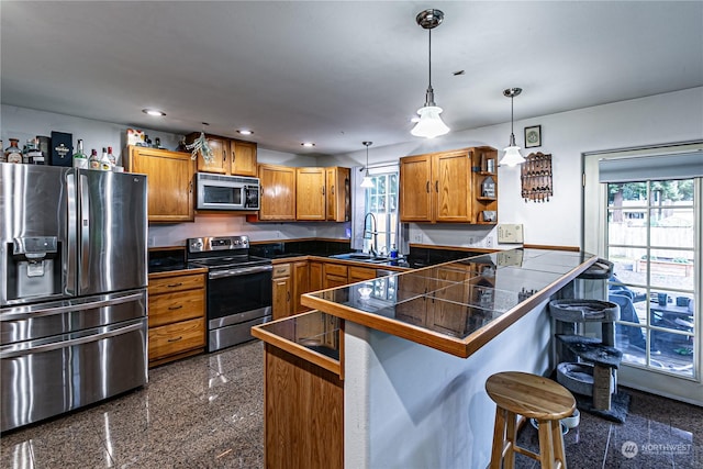 604 Nieland Loop SE, Rainier, WA 98576 - kitchen with stainless steel appliances, tile counters, a peninsula, a sink, and brown cabinets