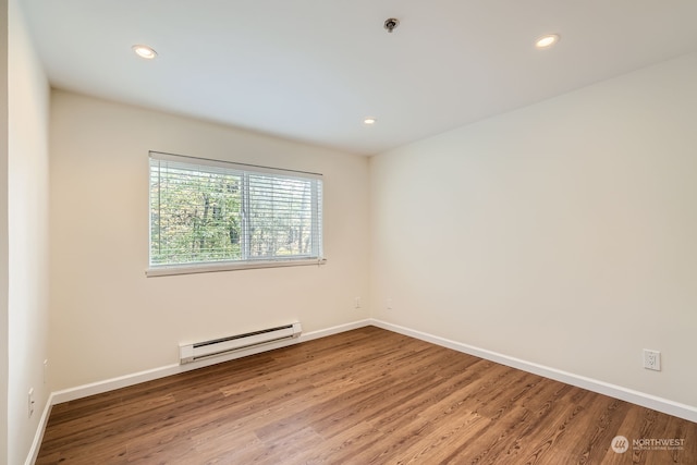 spare room featuring hardwood / wood-style flooring and a baseboard heating unit