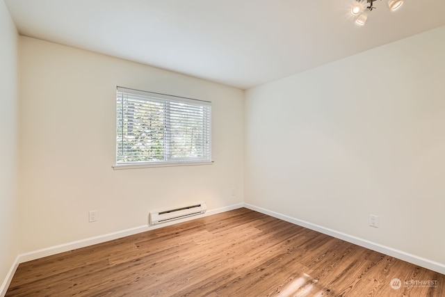 empty room with a baseboard heating unit and hardwood / wood-style floors