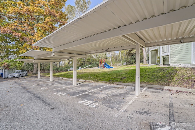 view of vehicle parking with a playground, a yard, and a carport