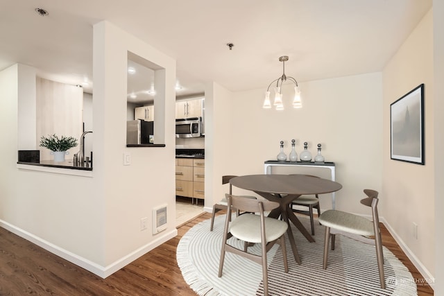 dining area with dark wood-type flooring and an inviting chandelier