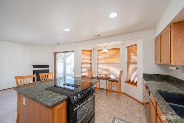 kitchen with light tile patterned floors, stainless steel dishwasher, dark stone countertops, black range with electric cooktop, and decorative light fixtures