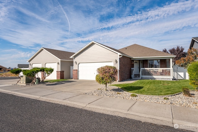 ranch-style house featuring covered porch, a front yard, and a garage