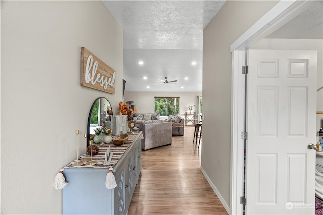 hallway with a textured ceiling and light wood-type flooring