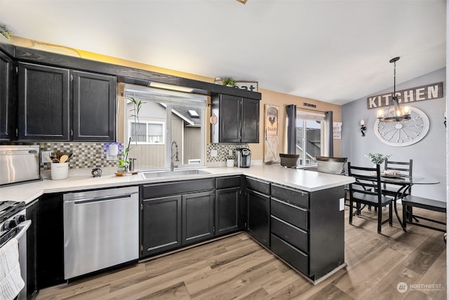 kitchen featuring light hardwood / wood-style flooring, sink, vaulted ceiling, pendant lighting, and appliances with stainless steel finishes