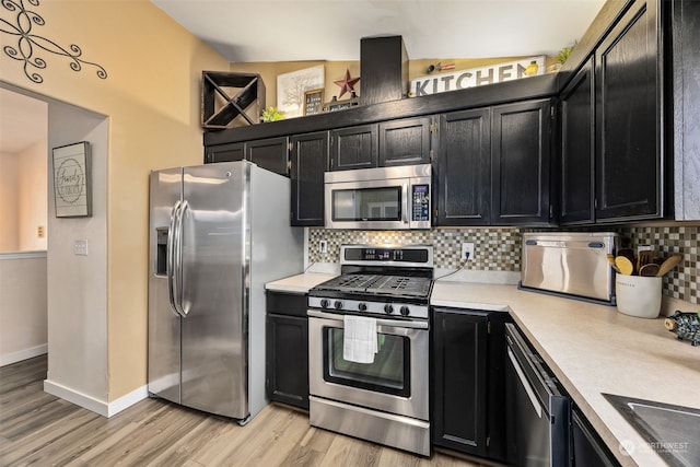 kitchen featuring light hardwood / wood-style flooring, tasteful backsplash, appliances with stainless steel finishes, and vaulted ceiling