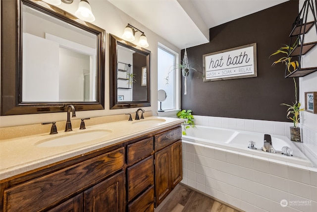 bathroom featuring vanity, wood-type flooring, and tiled bath