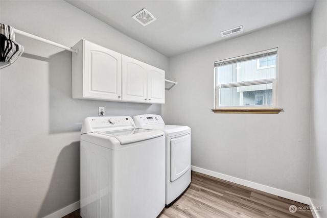 laundry room featuring cabinets, separate washer and dryer, and light wood-type flooring