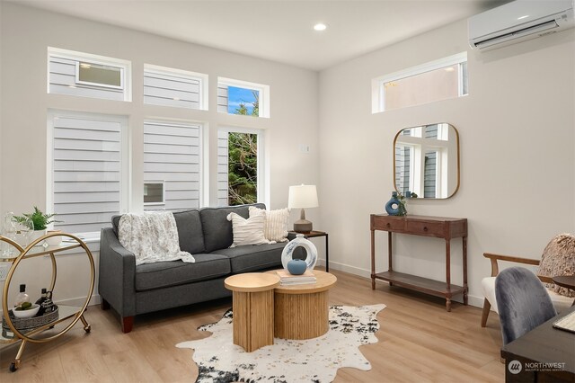 living room with light wood-type flooring, a high ceiling, and a wall unit AC