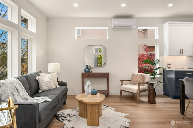 living room with a wall mounted air conditioner and light hardwood / wood-style floors