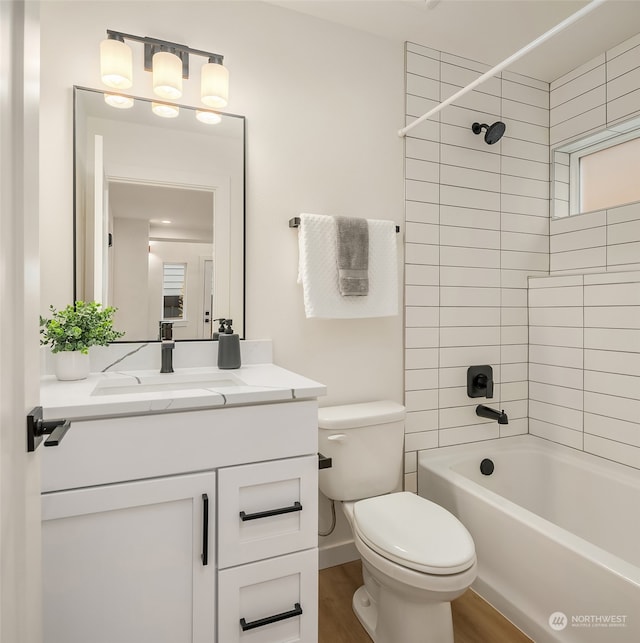 full bathroom featuring hardwood / wood-style floors, vanity, toilet, and tiled shower / bath combo