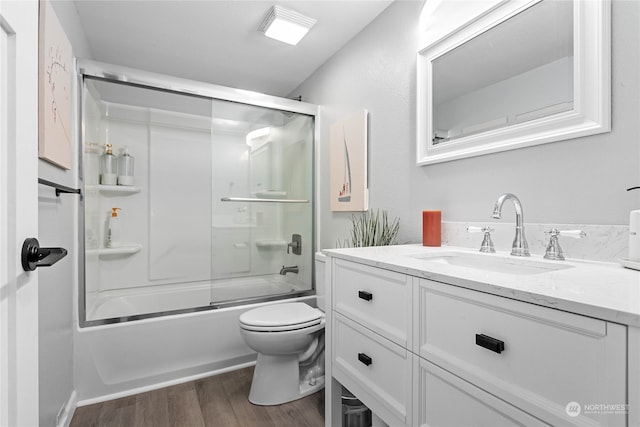 full bathroom with vanity, combined bath / shower with glass door, hardwood / wood-style flooring, and toilet