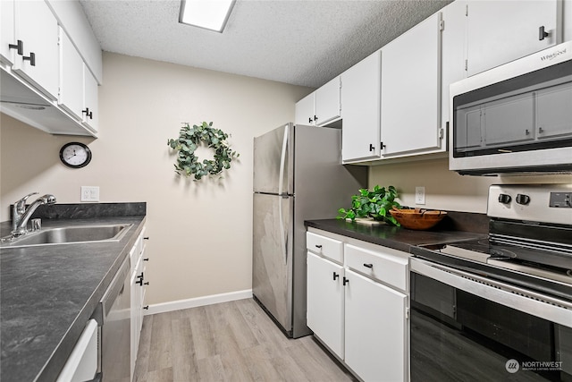 kitchen featuring sink, light wood-type flooring, white cabinetry, appliances with stainless steel finishes, and a textured ceiling