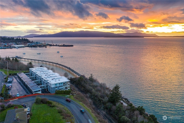 aerial view at dusk featuring a water and mountain view