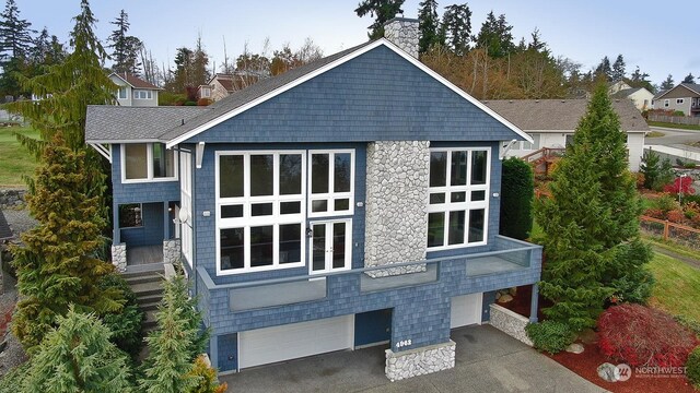 4962 Lilac Dr, Freeland, WA 98249 - back of property featuring an attached garage, a chimney, asphalt driveway, a shingled roof, and stone siding