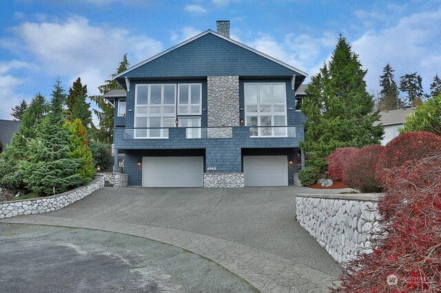 4962 Lilac Dr, Freeland, WA 98249 - view of front of home with stone siding, driveway, an attached garage, and a chimney