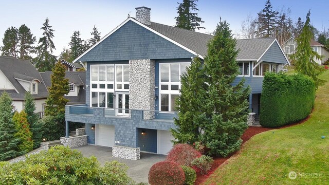 4962 Lilac Dr, Freeland, WA 98249 - back of property featuring a garage, driveway, stone siding, and a chimney
