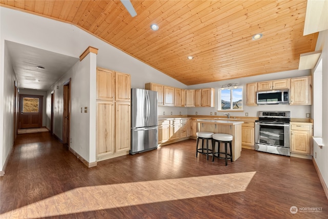 kitchen with appliances with stainless steel finishes, a breakfast bar area, vaulted ceiling, and a kitchen island