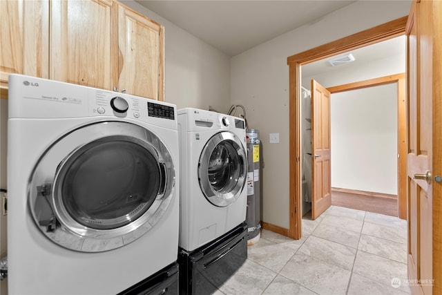 laundry room featuring electric water heater, independent washer and dryer, light tile patterned floors, and cabinets