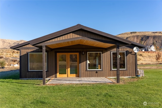 back of property with a mountain view and a lawn