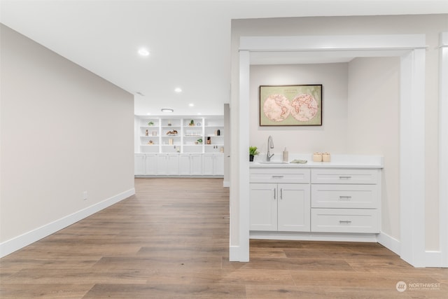 bar featuring white cabinets, sink, and light wood-type flooring