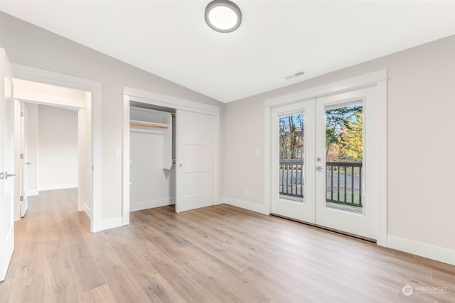 unfurnished bedroom with a closet, access to outside, french doors, light hardwood / wood-style floors, and lofted ceiling