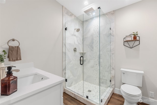 bathroom with hardwood / wood-style floors, vanity, toilet, and a shower with shower door