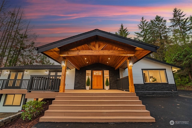 exterior entry at dusk with stone siding and a porch