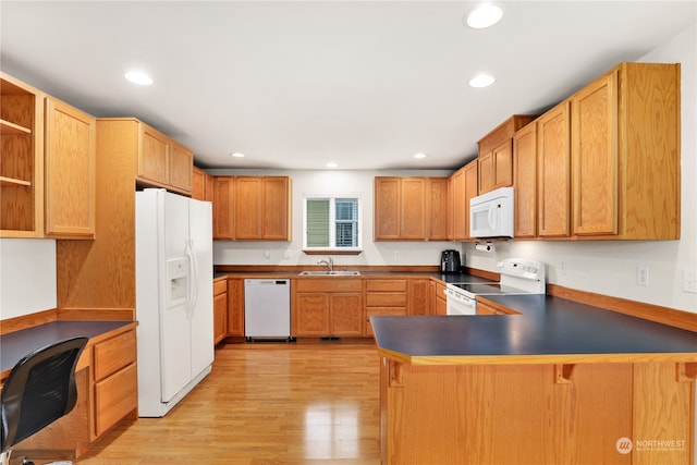 kitchen with a kitchen breakfast bar, kitchen peninsula, white appliances, sink, and light hardwood / wood-style floors