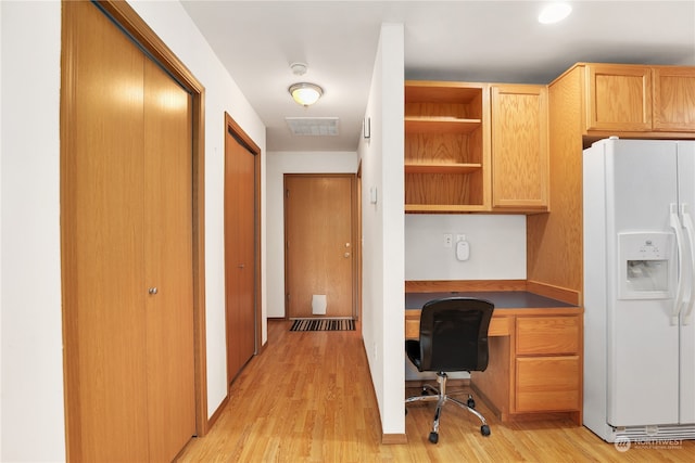 unfurnished office with built in desk and light hardwood / wood-style flooring