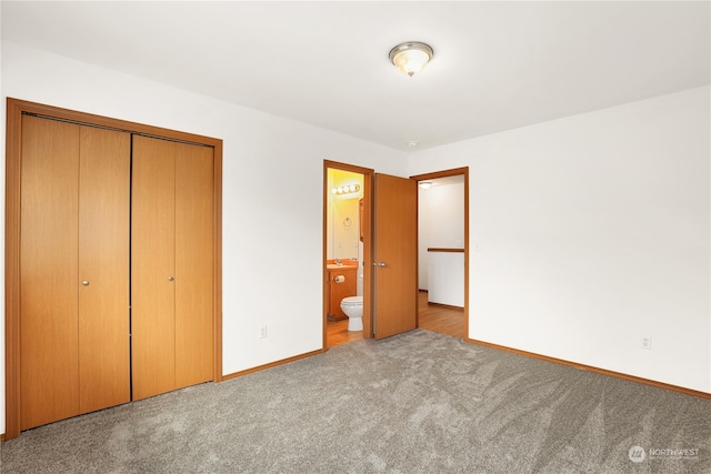 unfurnished bedroom featuring a closet, ensuite bathroom, and light carpet