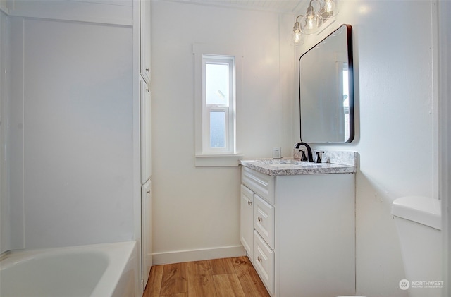 bathroom with vanity, a tub to relax in, toilet, and wood-type flooring