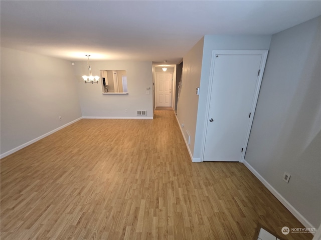 empty room with an inviting chandelier and light wood-type flooring