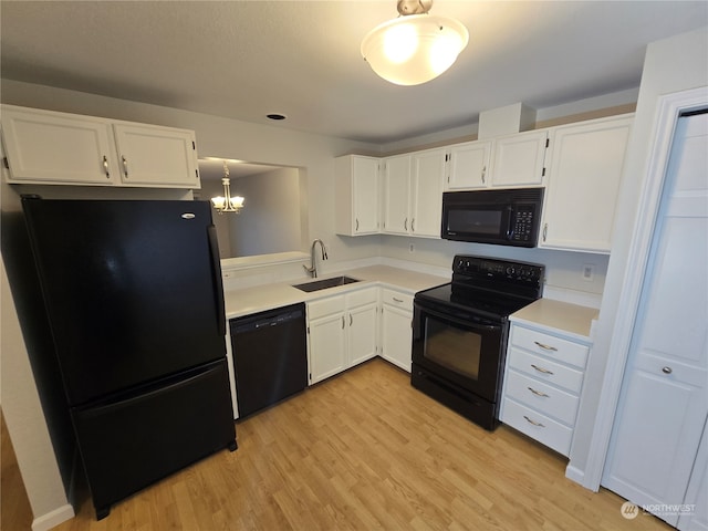 kitchen featuring hanging light fixtures, white cabinetry, black appliances, light hardwood / wood-style floors, and sink