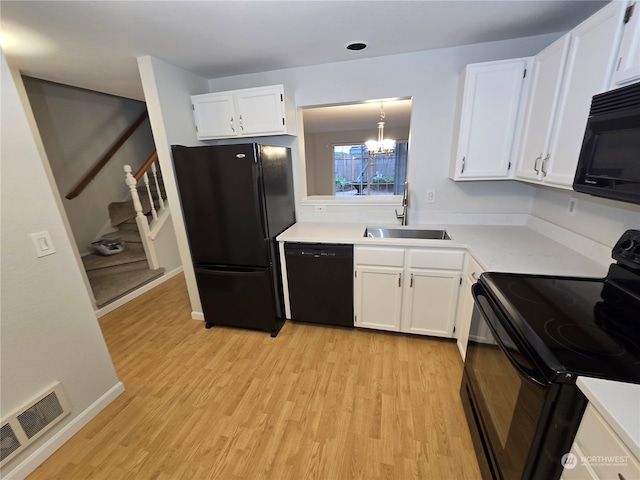 kitchen with white cabinets, black appliances, sink, and pendant lighting