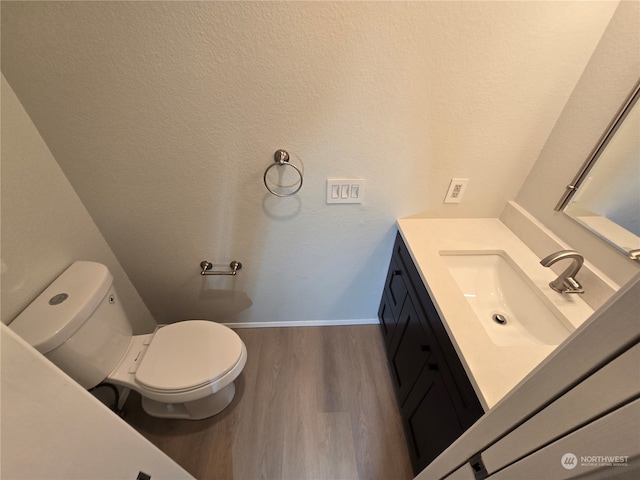 bathroom featuring toilet, hardwood / wood-style flooring, and vanity