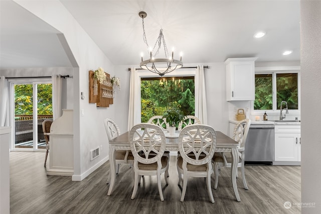 dining room featuring an inviting chandelier, sink, wood-type flooring, and vaulted ceiling