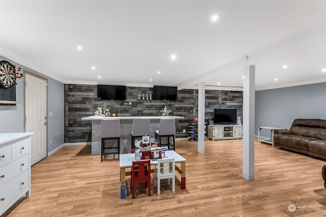 kitchen with crown molding, a kitchen bar, light wood-type flooring, and white cabinets