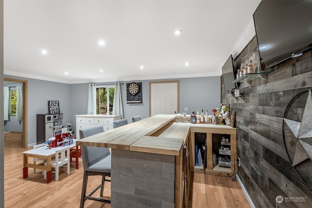 bar featuring crown molding, light hardwood / wood-style flooring, and wood counters